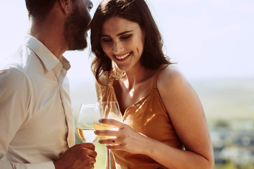 A couple smiling, drinking wine on one of the most romantic getaways in Pennsylvania