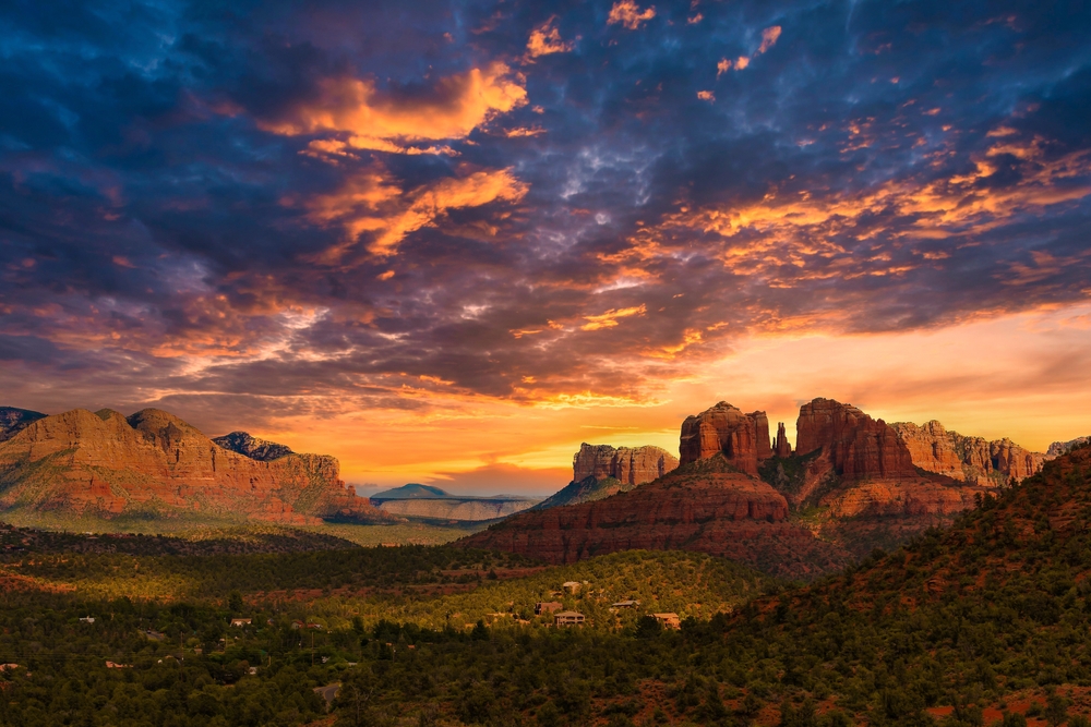 the iconic red rocks of sedona arizona seen from a distant. an epic landscape with a vibrant purple and pink sunset over head