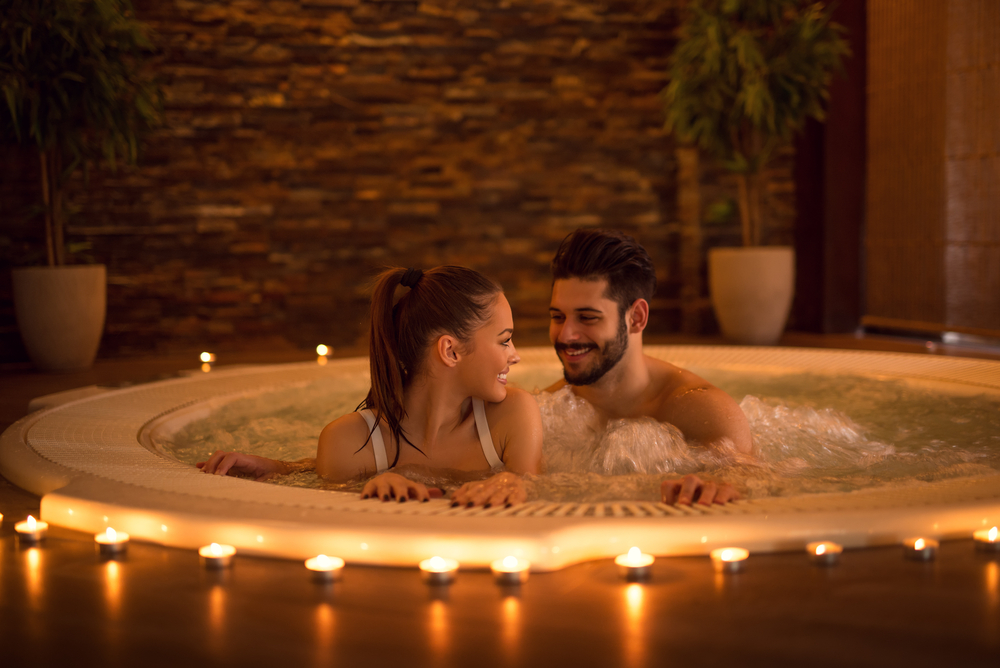 A man and a woman share a hot tub surrounded by candles during a romantic couples trip in Ohio