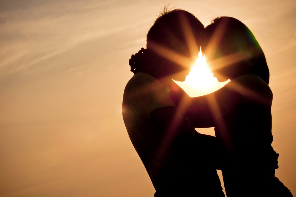 The silhouette of a couple embracing with the sun behind them