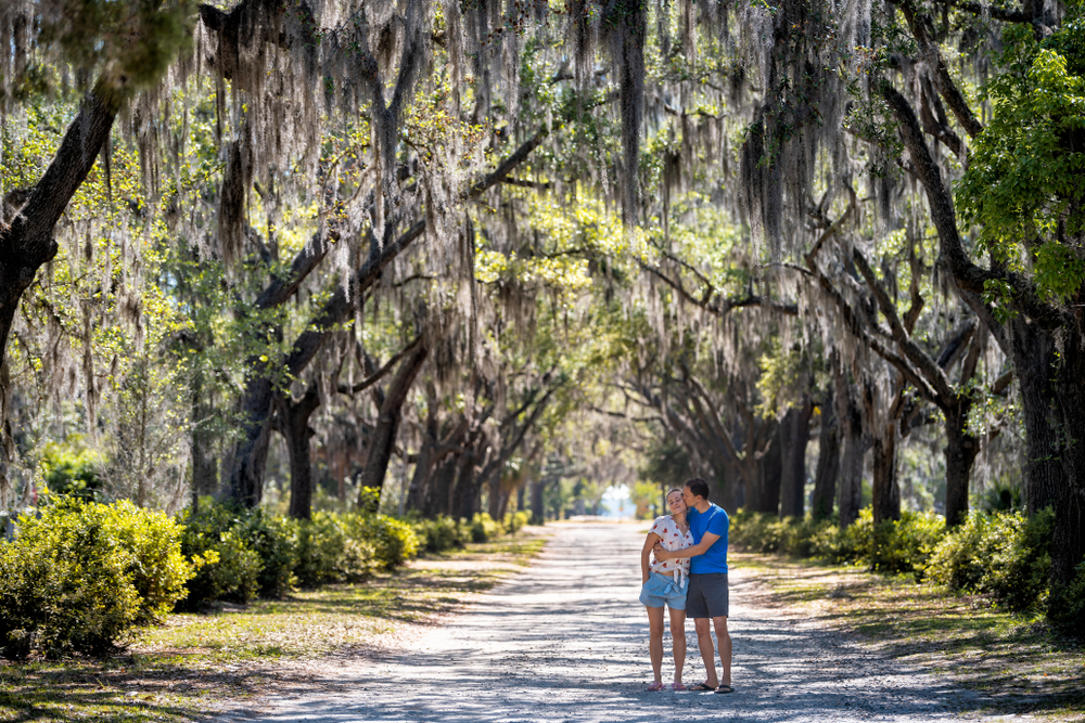 A couple embraces in Savannah under Live Oak trees during one of the top romantic getaways in Georgia