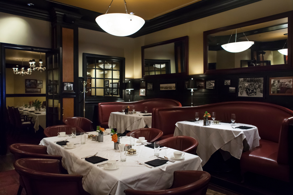 An elegant restaurant at a romantic Atlanta hotel is seen with mood lighting and white linens