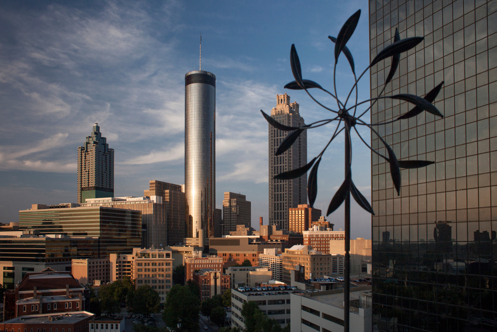 An aerial view of the Westin Peachtree Plaza and other tall skyscrapers in Atlanta Georgia with a blue sky behind