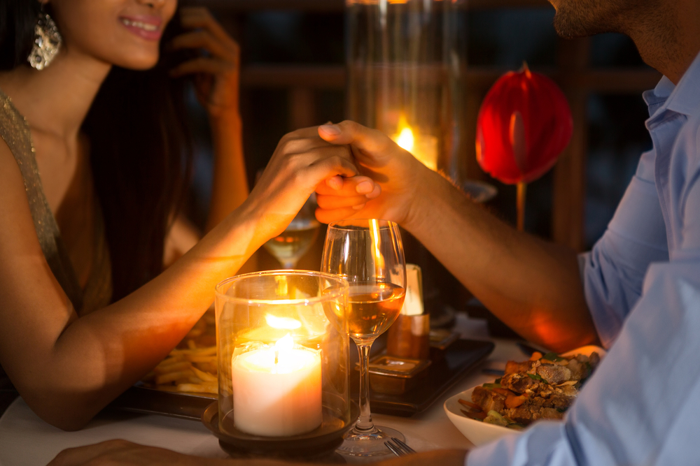 A couple holds hands while enjoying a nice candelit romantic dinner at one of the most romantic hotels in Atlanta, Georgia.